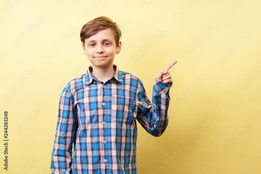 look there. cute boy pointing sideways with hand over yellow background, advertisement, banner or poster template, emotion facial expression, people reaction look there. cute boy pointing sideways with hand over yellow background, advertisement, banner or poster template, emotion facial expression, people reaction