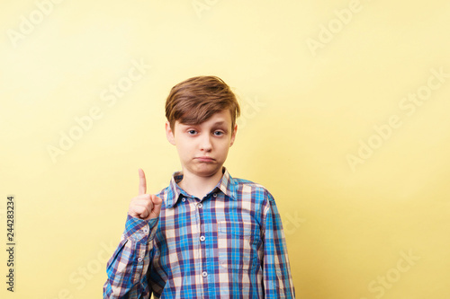look there. approval. cute boy pointing upwards with index finger over yellow background, advertisement, banner or poster template, emotion facial expression, people reaction