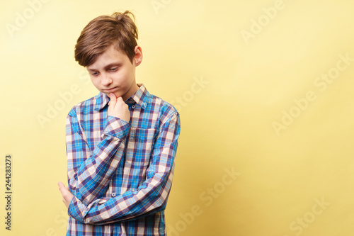 pondering contemplating pensive boy thinking of something over yellow background, advertisement, banner or poster template, emotion facial expression, people reaction