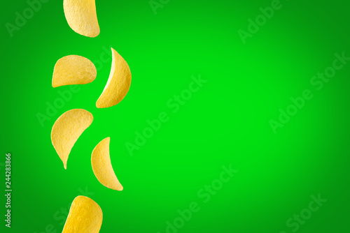 Falling potato chips isolated on green background. Flying crispy snacks