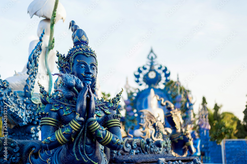 closeup buddha statue in rong sua ten temple (blue temple) with soft-focus and over light in the background, Chiang Rai Province, Thailand