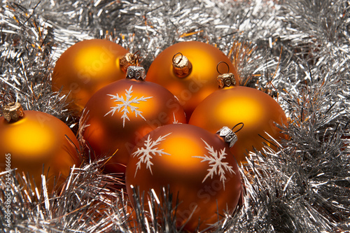 Group of orange bauble Christmas decorations on silver tinsel.