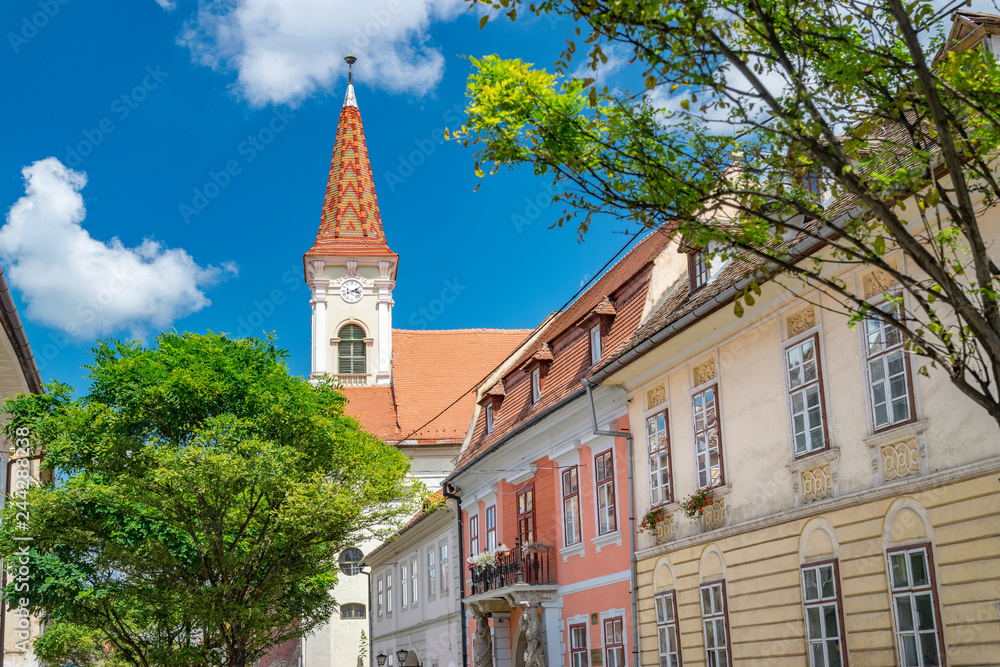 Fototapeta premium Sibiu, Romania - Beautiful street with Reformed Church on a sunny summer day in Sibiu, Romania