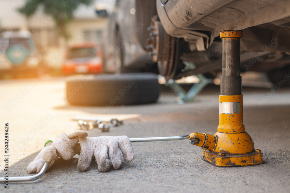Jacking up a car with the emergency jack,Auto mechanic changing tire on car on road ,copy space