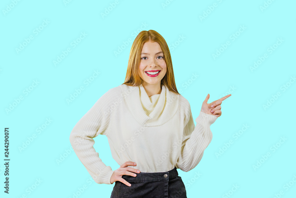 A beautiful girl with red hair is smiling and showing the index finger to the side on A beautiful girl with red hair is smiling and showing the index finger to the side on