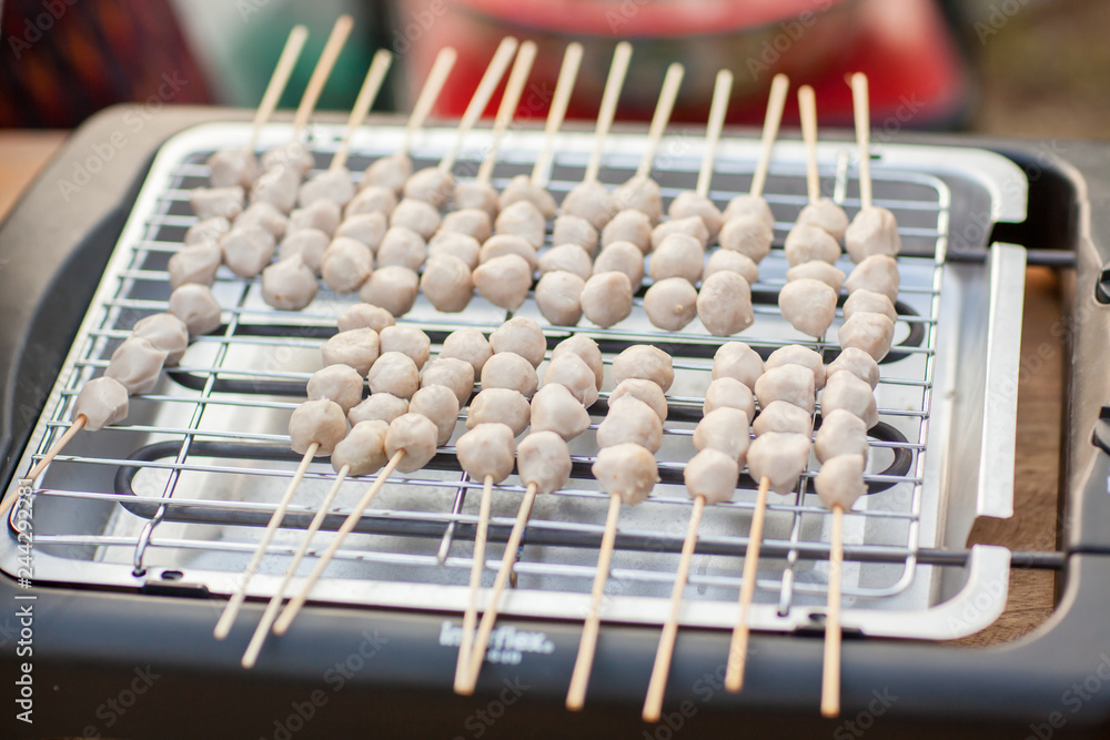 Grilled meat ball with sweet spicy sauce on wood dish. Selective focus. grilled pork meatballs with sweet chili sauce on plate. Meat ball on grill / meat ball and pork ball skewer roast on the stove