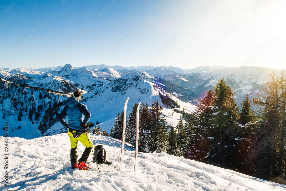 Skier man looking the sunset in the summit of Austrian Alps in a beautiful sunny day.
