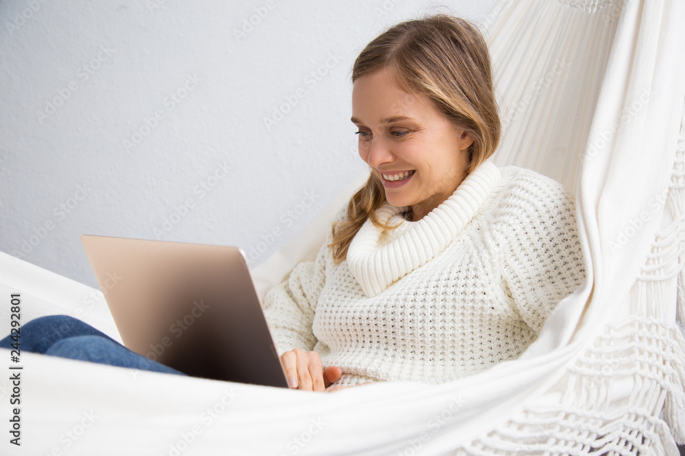 Happy student sitting in hammock and using laptop. Smiling young woman working at home. Technology concept Happy student sitting in hammock and using laptop. Smiling young woman working at home. Technology concept