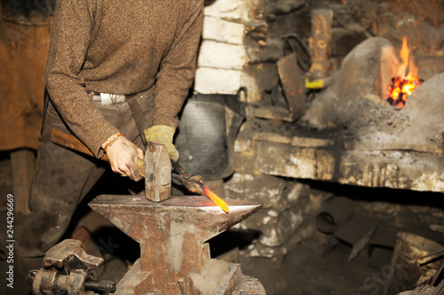 Blacksmith working metal with hammer on the anvil
