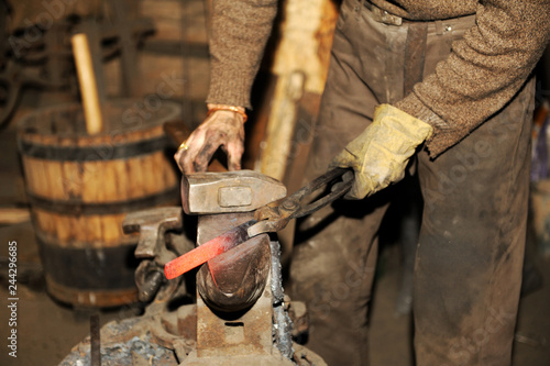 Fototapeta Naklejka Na Ścianę i Meble -  Blacksmith working metal with hammer on the anvil