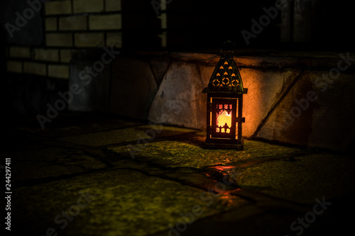 Beautiful colorful illuminated lamp in the garden in misty night. Retro style lantern at night outdoor.