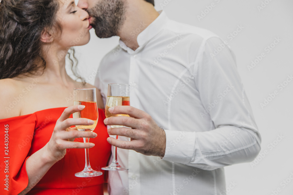 Loving young couple drinks champagne. On a white background. Dressed in red dress and white shirt. Loving young couple drinks champagne. On a white background. Dressed in red dress and white shirt.