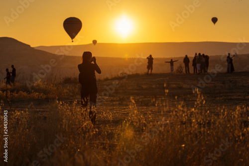 People taking pictures and enjoying balloons at sunrise in Cappadocia, Turkey.