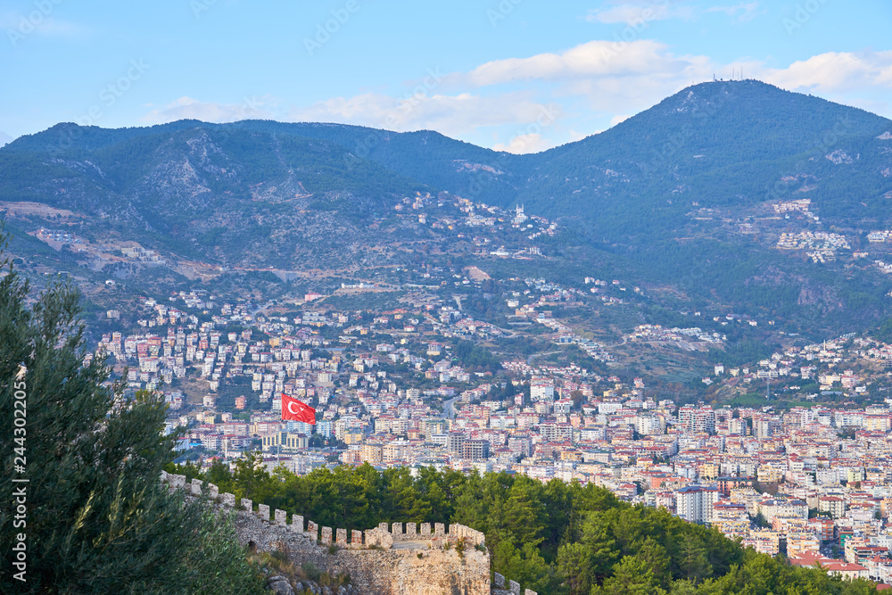 Flag of Turkey over Alanya and medieval wall.