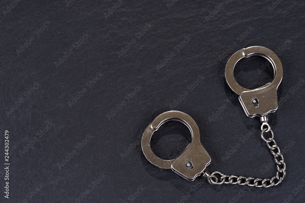 Closed silver handcuffs isolated on black background Closed silver handcuffs isolated on black background