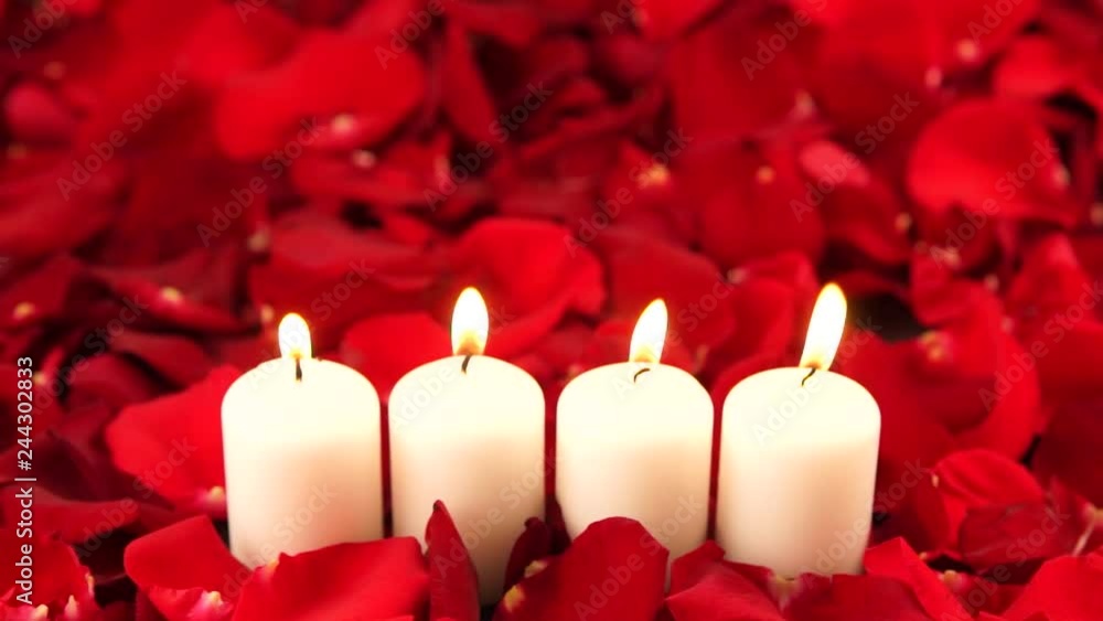 four burning candles stand in red rose petals four burning candles stand in red rose petals