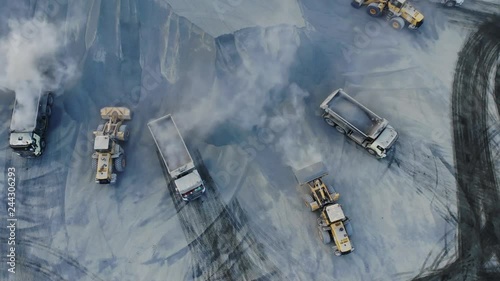 AERIAL. Top angle view of big career and excavators pours sand into the truck. On the construction site top view. Shooting from the drone.