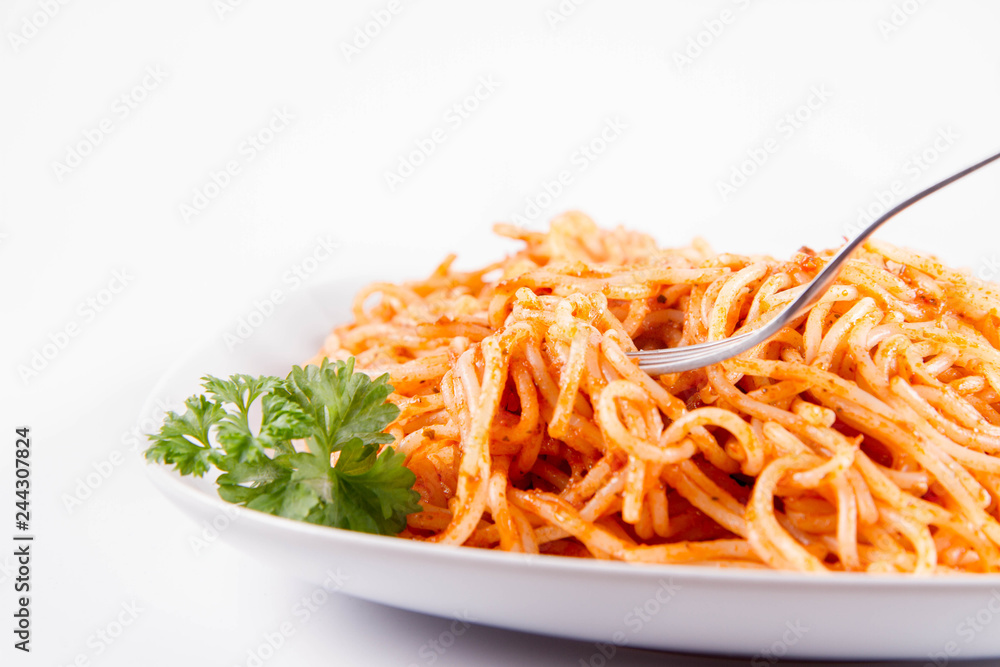 Spaghetti with pesto rosso decorated with parsley eaten with a fork on a white background Spaghetti with pesto rosso decorated with parsley eaten with a fork on a white background