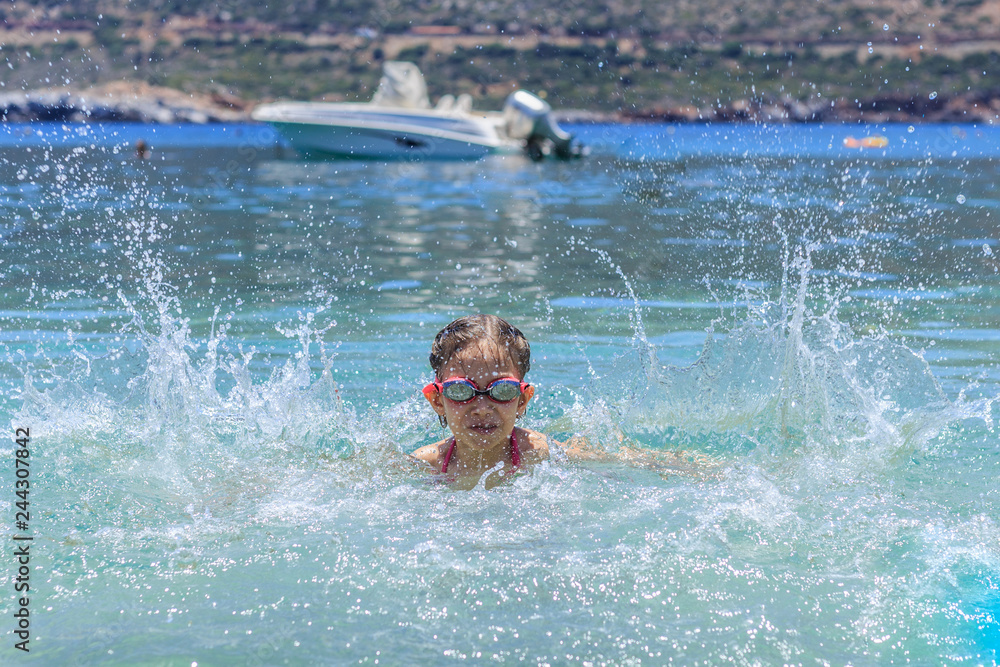 Young girl at yhe sea having fun and splashing water in summer