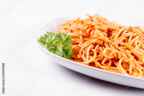 Spaghetti with pesto rosso decorated with parsley on a white background