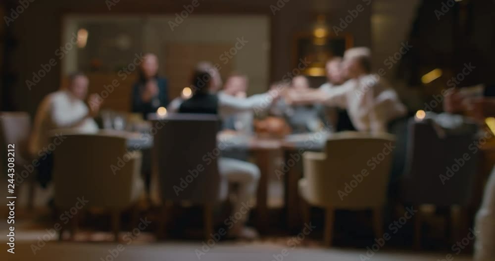 DEFOCUSED BACKGROUND Large multi-generation family clinking glasses while having Christmas or Thanksgiving dinner. 4K UHD Blackmagic RAW DEFOCUSED BACKGROUND Large multi-generation family clinking glasses while having Christmas or Thanksgiving dinner. 4K UHD Blackmagic RAW