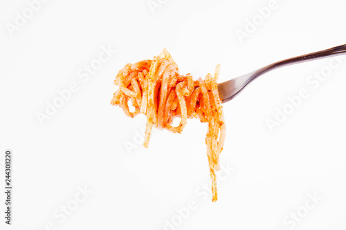 Spaghetti with pesto rosso on a fork on a white background