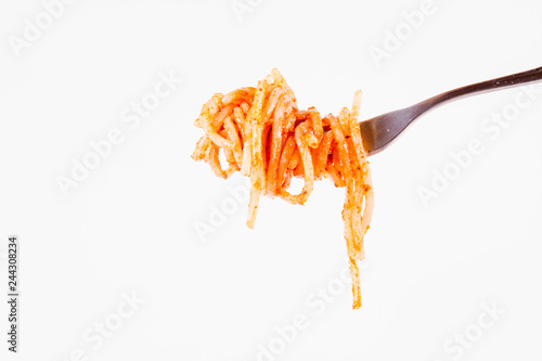 Spaghetti with pesto rosso on a fork on a white background