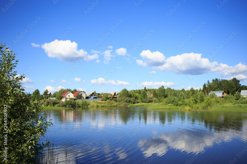 Lake reflecting sky with clouds on it flowing through a small village