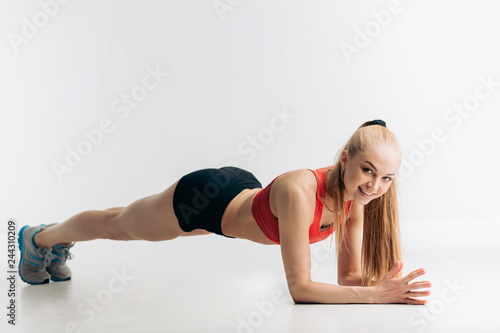 cheerful blonde athlete showing plank exercises for tight, flat abs, full length side view shot
