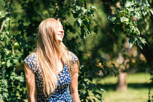Happy woman with beautiful blonde hair smiling in the summer park