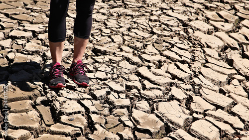A women standing on a dry cracked river bed. Drought concept image. 