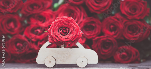 Concept Valentine day, love, machine transports a flower on the background of red roses. Stylish love concept, space for text.