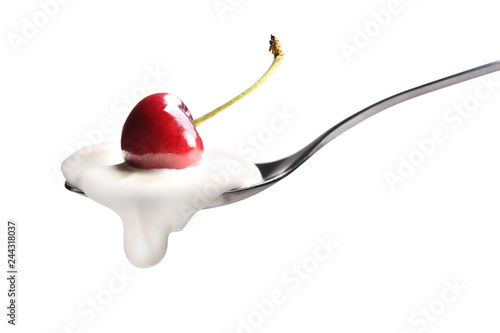 Plain yogurt on a spoon with fresh cherry on top isolated on white background