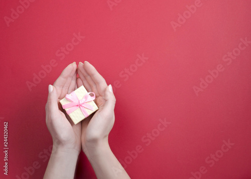 A small gift with a pink bow in women's hands photo