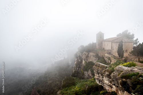 Iglesia de Santa María en la niebla de la ciudad medieval de Ciurana o Siurana sobre el riscal de la Sierra de la Gritella