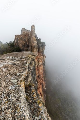 Ruinas en la niebla del castillo de la ciudad medieval de Ciurana o Siurana sobre el riscal de la Sierra de la Gritella photo