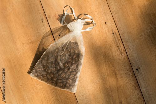 Coffee beans sourvenir in a small bag on wooden background, Wedding sourvenir concepts photo