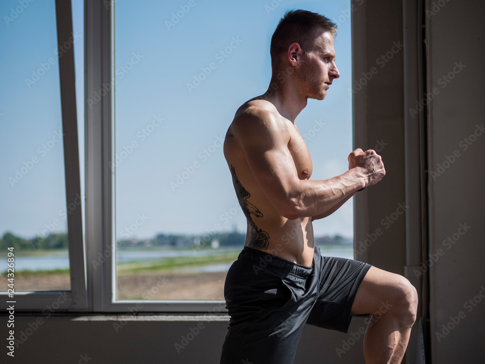 Obraz premium Young aerobics male coach shirtless leaning on step in gym