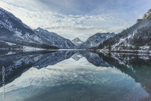 Winterliches Alpenpanorama mit glasklarer Spiegelung von Gipfel im See, Plansee, Tirol, Österreich
