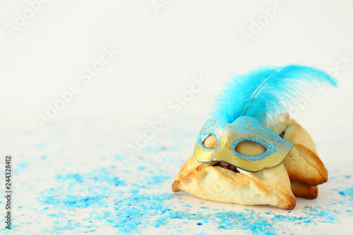 Fototapeta Naklejka Na Ścianę i Meble -  Purim celebration concept (jewish carnival holiday). Traditional hamantaschen cookies with beautiful blue and gold mask over white wooden table.