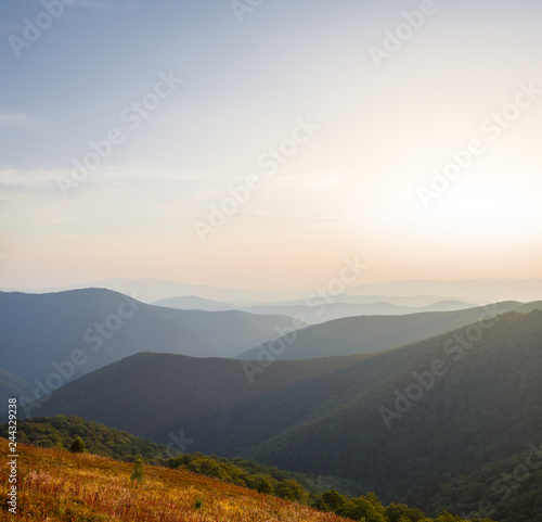 beautiful quiwt mountain valley at the sunset, mountain chain silhouette in a blue mist
