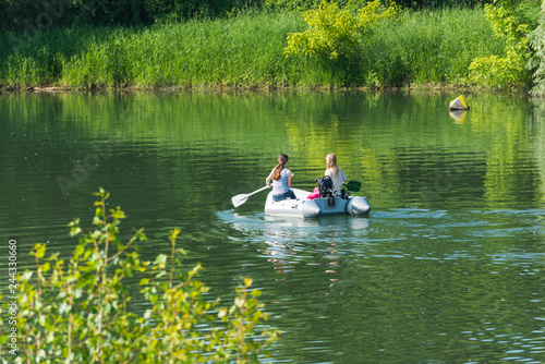 Zwei M  dchen paddeln in einem Schlauchboot auf einem See