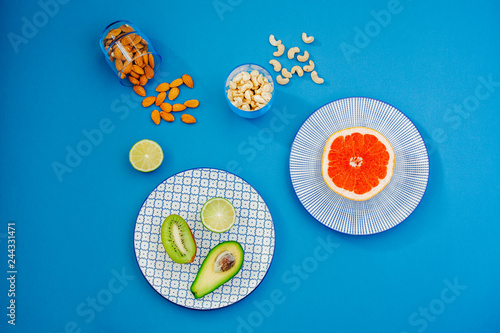 Top view of fresh grapefruit, avocado, limes and kiwi on bright blue background