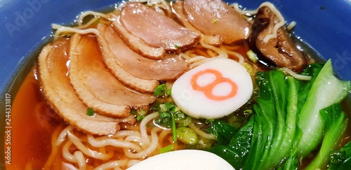 Close up hot Hachiban ramen noodle with roasted pork sliced and tasty soup in blue bowl on wooden table with left copy space at Japanese restaurant - Healthy life style eating and Asian food concept   photo