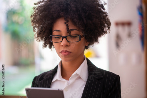 Successful young African American businesswoman looking focused while working on a digital tablet in her home office