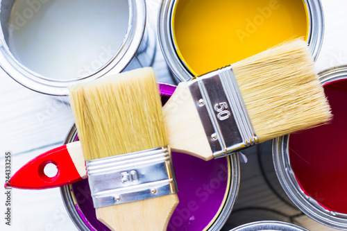 House renovation concept, colorfull paint cans and paintbrushes on wooden background