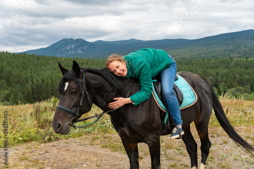 A beautiful girl lies on a horse and laughs very much. Life is beautiful and nature too. Fresh air