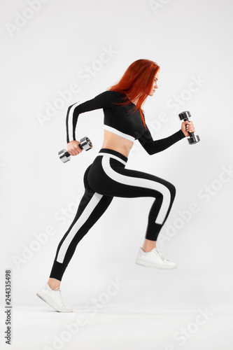 Sporty fit woman, athlete runner makes fitness exercising with dumbbells on white background. © Mike Orlov