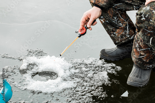 A young man is fishing from a hole on ice. Winter fishing