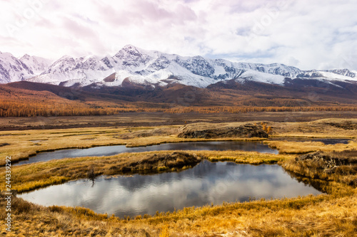 Autumn panorama. View of mountains and lake. Mountain range on horizon. Travel to mountain valley with rivers.